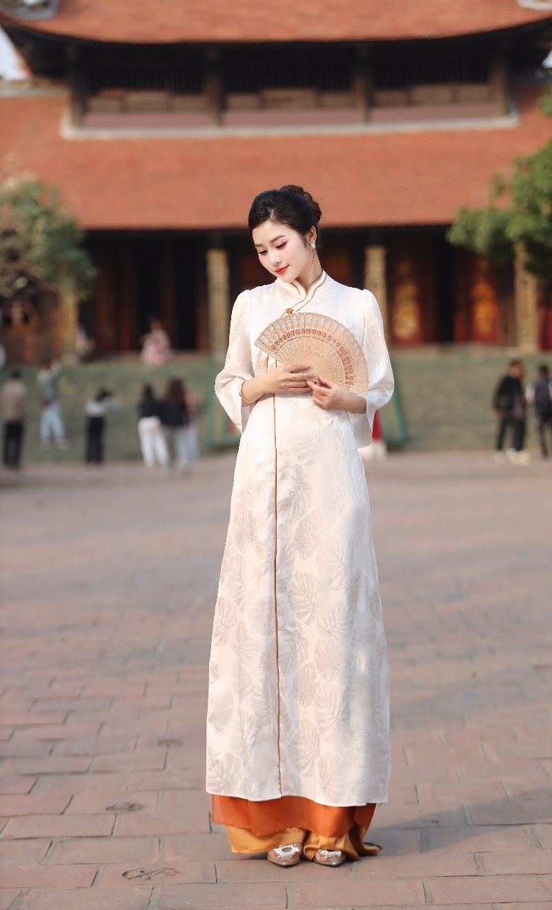 Áo Dài Gấm Trắng Ngà Viền Cam Đất – Nét Chấm Phá Đương Đại Trên Nền Cổ Điển